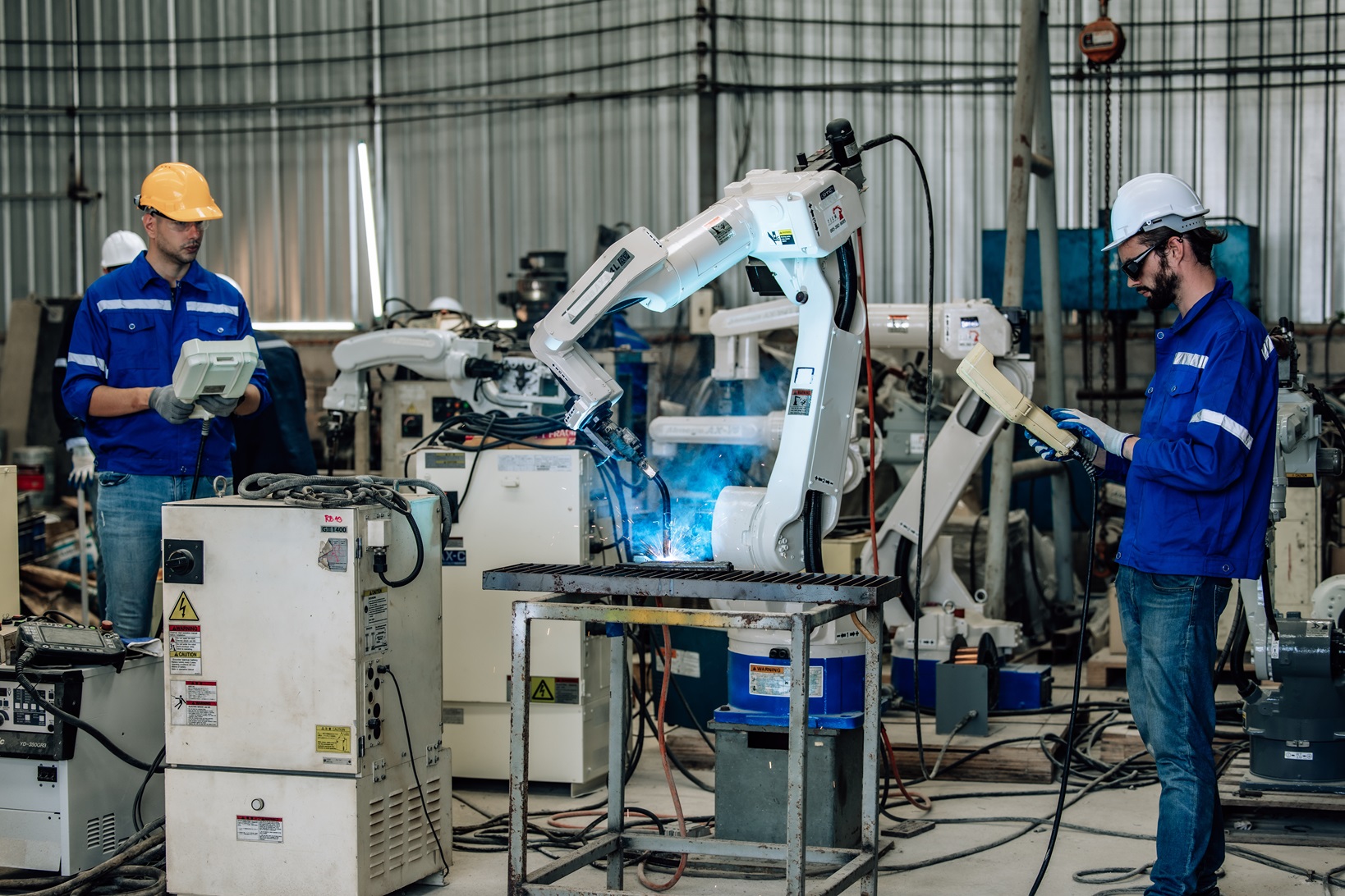 Two highly competent robotic operators collaborate to configure new automation using a computer-controlled panel display. The robot’s coordination system for welding, cutting, and milling in a factory